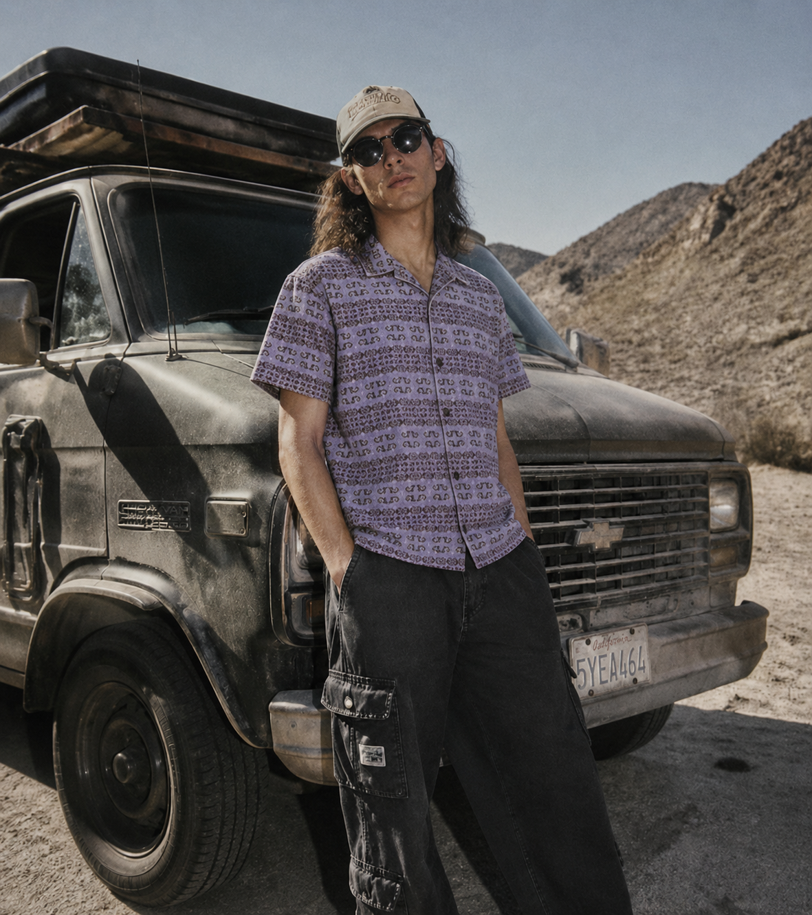 Ape Outfitters model in the Ape Tribe revere shirt leaning against a Chevy van in the Mojave desert